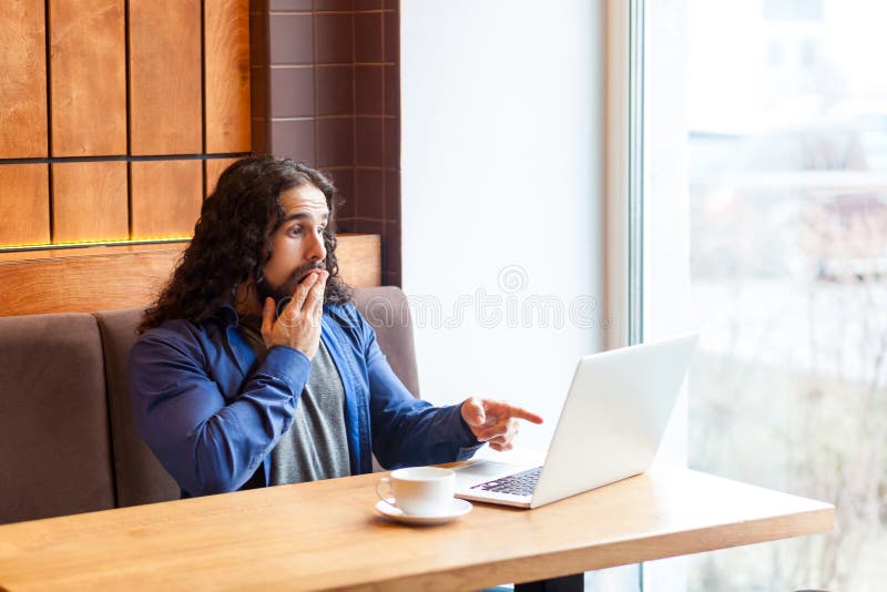 U die kidding! Verraste jonge volwassen mens freelancer in toevallige stijlzitting in koffie en het spreken met vrienden in lapto stock foto's U die kidding! Verraste jonge volwassen mens freelancer in toevallige stijlzitting in koffie en het spreken met vrienden in lapto stock foto's