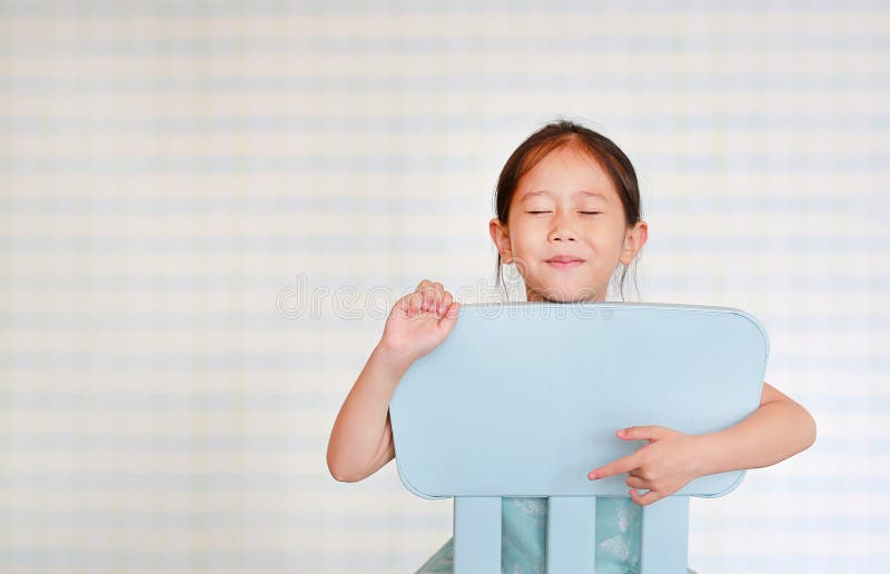 U?miechni?tego ma?ego Azjatyckiego dziecka preschool dziewczyna w dziecina pokoju pozach na plastikowym dziecka krze?le zdjęcie royalty free U?miechni?tego ma?ego Azjatyckiego dziecka preschool dziewczyna w dziecina pokoju pozach na plastikowym dziecka krze?le zdjęcie royalty free