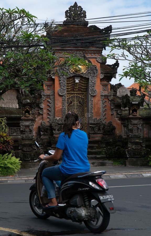Ubud Bali, Indonesien Maj 3, 2019: Den oidentifierade kvinnan rider motorsparkcykeln i Ubud, Bali, Indonesien royaltyfria bilder Ubud Bali, Indonesien Maj 3, 2019: Den oidentifierade kvinnan rider motorsparkcykeln i Ubud, Bali, Indonesien royaltyfria bilder