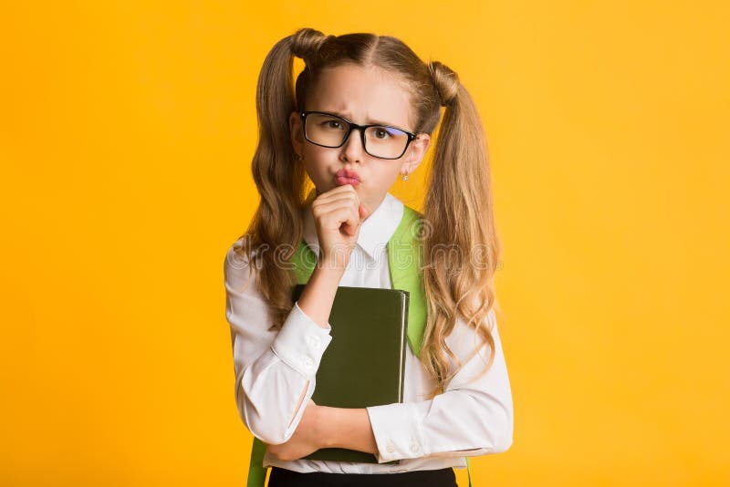 Let Me Think Concept. Schoolgirl Bethinking Touching Chin Holding Books On Yellow Studio Background. Free Space. Let Me Think Concept. Schoolgirl Bethinking Touching Chin Holding Books On Yellow Studio Background. Free Space