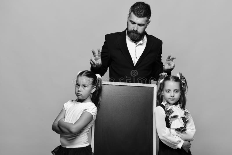 Uczennicy zbliżają blackboard i faceta na żółtym tle tylna koncepcji do szkoły Dziewczyny i mężczyzna z poważnymi twarzami zdjęcie royalty free Uczennicy zbliżają blackboard i faceta na żółtym tle tylna koncepcji do szkoły Dziewczyny i mężczyzna z poważnymi twarzami zdjęcie royalty free