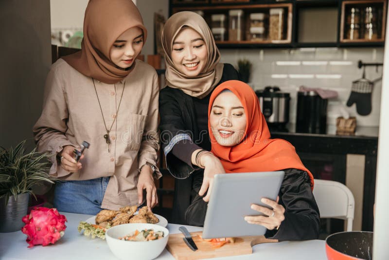 Three muslim friend looking tablet and learn to make new food menu in the kitchen. cooking recipe. Three muslim friend looking tablet and learn to make new food menu in the kitchen. cooking recipe