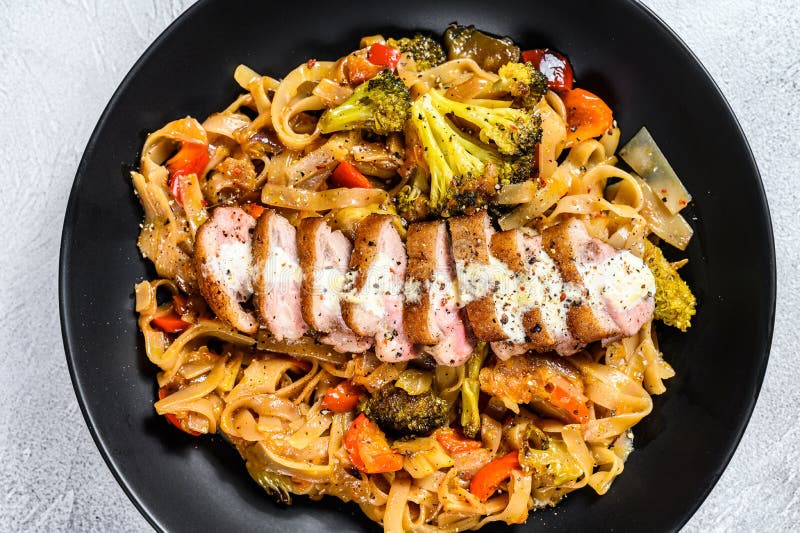Udon noodles with grilled duck breast. Gray background. Top view