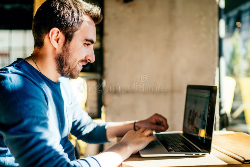 Ufny mężczyzna pracuje od kawiarni na laptopie i smil, pisać na maszynie zdjęcia royalty free Ufny mężczyzna pracuje od kawiarni na laptopie i smil, pisać na maszynie zdjęcia royalty free