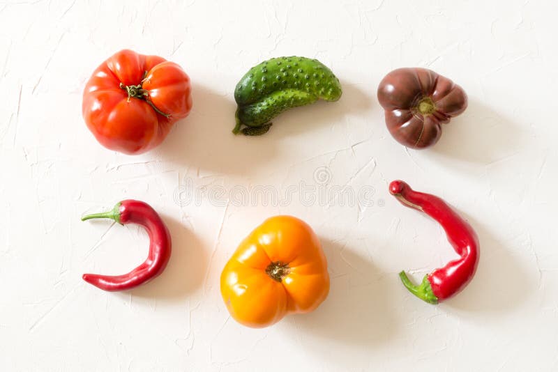 Ugly organic colorful tomato, pepper, cucumber on white concrete table stock photos
