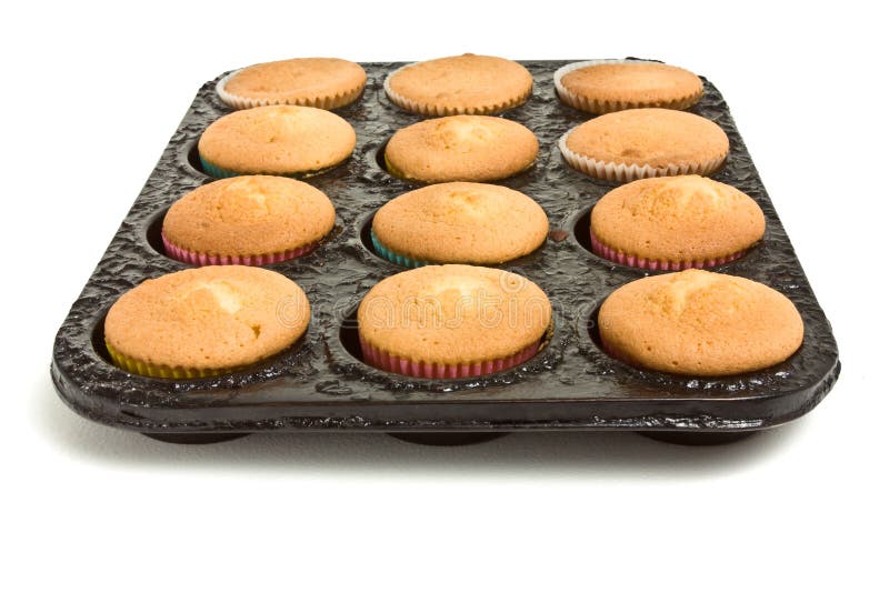 Freshly cooked cup cakes still in baking tray straight from the oven on white. Freshly cooked cup cakes still in baking tray straight from the oven on white.