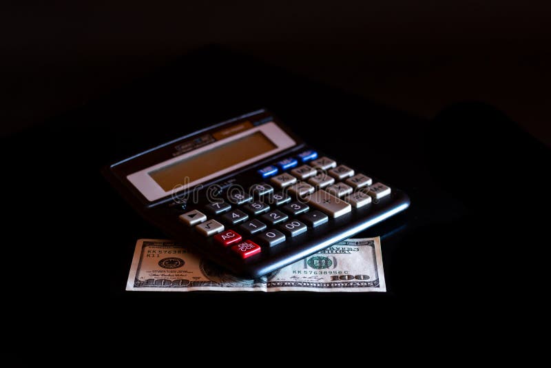 Uitgavenkosten, begroting en belasting of investeringsberekening, dollar honderd met calculator op donkere zwarte lijst als achte royalty-vrije stock afbeeldingen Uitgavenkosten, begroting en belasting of investeringsberekening, dollar honderd met calculator op donkere zwarte lijst als achte royalty-vrije stock afbeeldingen