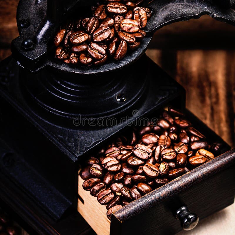 Uitstekende handkoffiemolen met koffiebonen op houten bruin royalty-vrije stock afbeeldingen Uitstekende handkoffiemolen met koffiebonen op houten bruin royalty-vrije stock afbeeldingen
