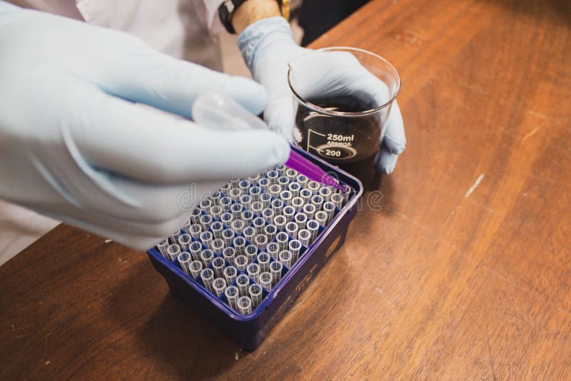 Ujęcie pod wysokim kątem asystenta laboratoryjnego dodającego purpurowy płyn do probówek. Ujęcie pod wysokim kątem asystenta laboratoryjnego dodającego fioletowy płyn do probówek w Laboratorium Robotyki w Bristolu