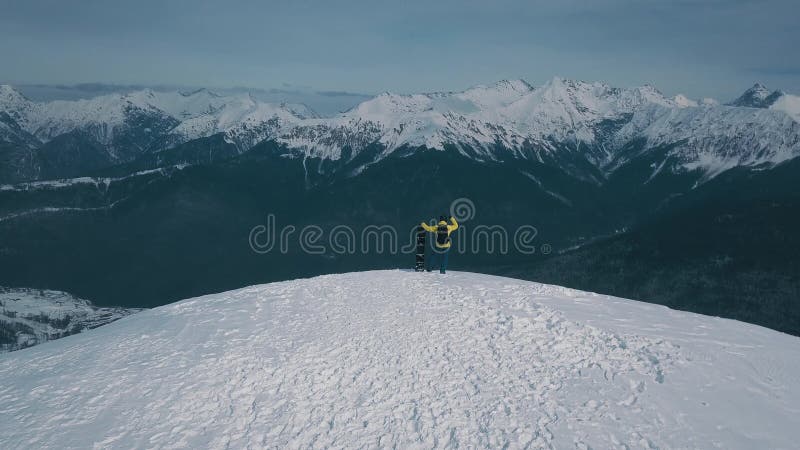 Ujęcie z lotu ptaka nad zwycięzcą męskiego snowboardu podziwiającego górski krajobraz z szczytu skały