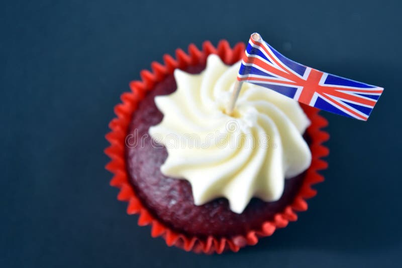 UK celebration cake, party food with red, white and blue cupcake and british flag. Celebration, patriotism and holidays concept - close up of glazed muffin decorated with british flag. UK celebration cake, party food with red, white and blue cupcake and british flag. Celebration, patriotism and holidays concept - close up of glazed muffin decorated with british flag