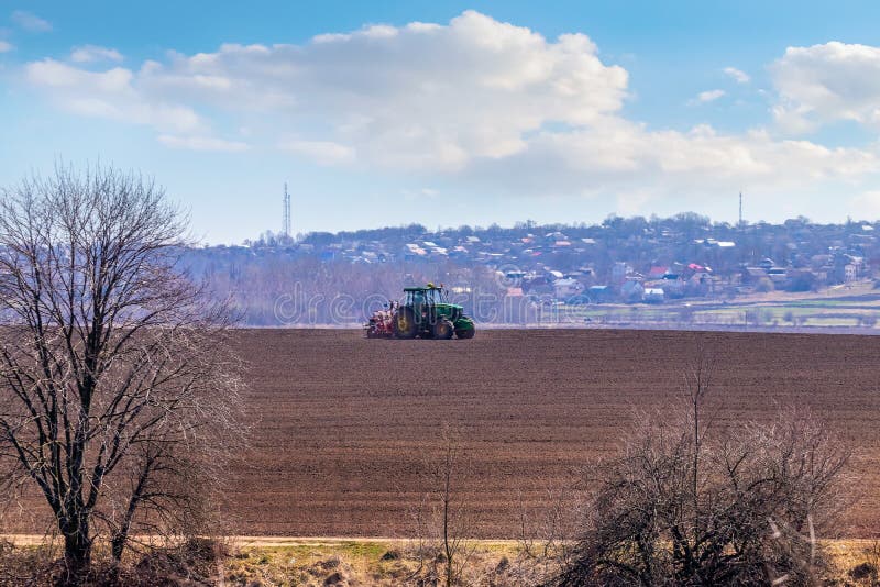 Ukraine, Khmelnytsky region, March 2021. Tractor with a seeder in the field during sowing of grain