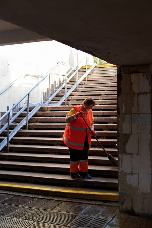 Ukraine, Kiev - September 12, 2019: A cleaning lady is sweeping a staircase in a subway underpass royalty free stock photography Ukraine, Kiev - September 12, 2019: A cleaning lady is sweeping a staircase in a subway underpass royalty free stock photography