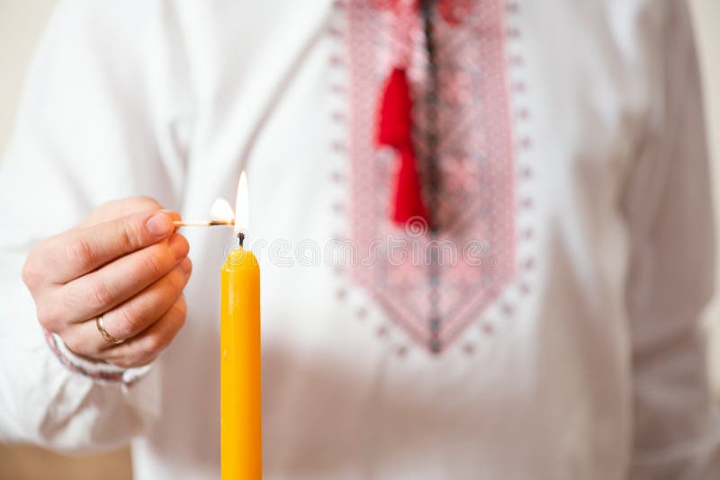 Ukrainian man in embroidered shirt lights a candle. Themes of celebrating Easter or Christmas, Day of memory of the victims of the royalty free stock photos Ukrainian man in embroidered shirt lights a candle. Themes of celebrating Easter or Christmas, Day of memory of the victims of the royalty free stock photos