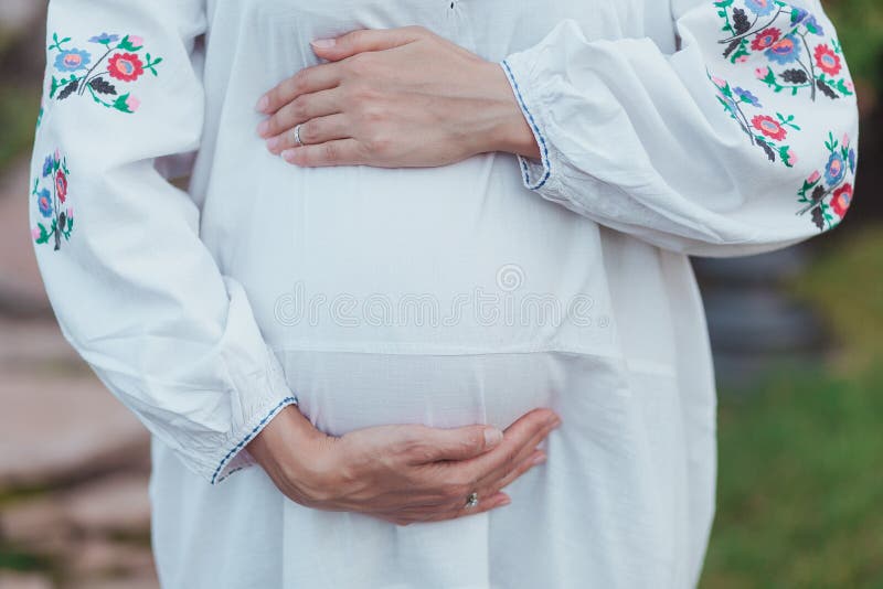 Ukrainian pregnant woman wear traditional embroidered shirt. Location in traditional ukrainian village.