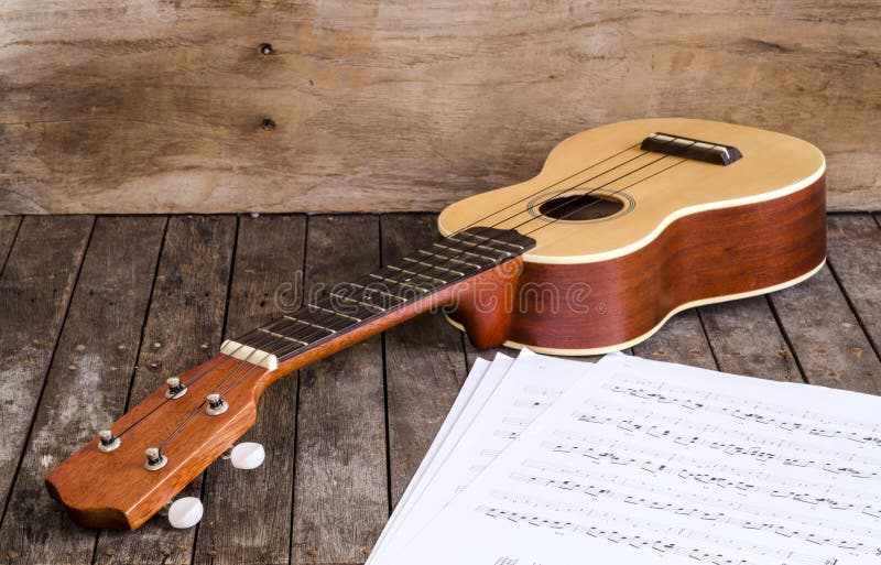 Ukulele and Paper Chordschart document on wooden background. stock photos