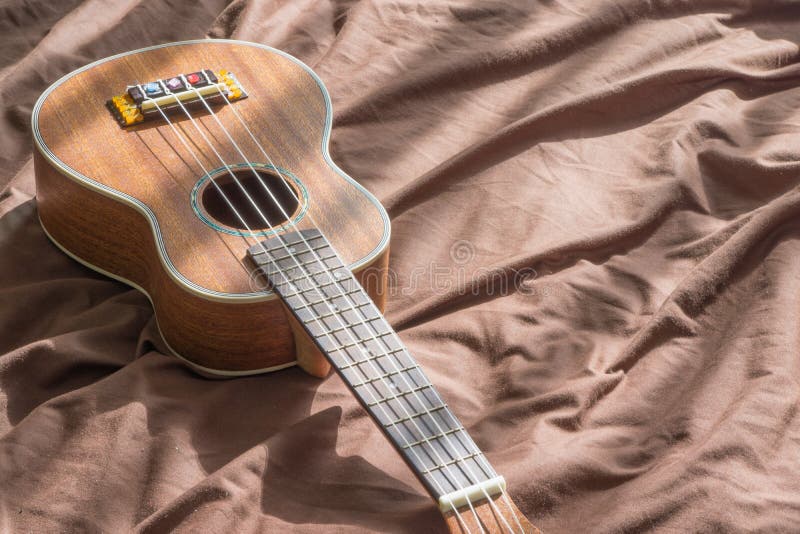 Ukulelegitarre auf Betthintergrund lizenzfreies stockfoto Ukulelegitarre auf Betthintergrund lizenzfreies stockfoto