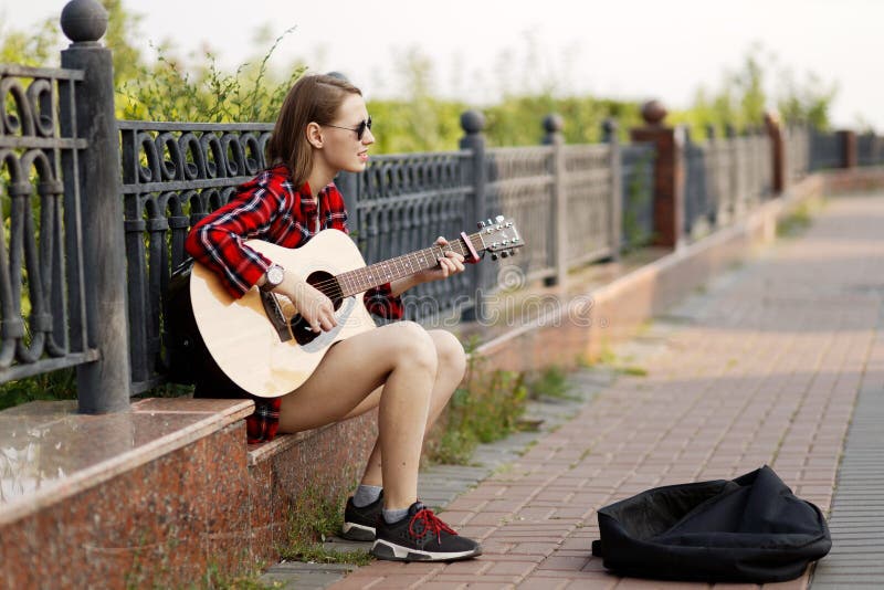 Uliczna muzyk młoda kobieta bawić się gitarę akustyczną i śpiew w miasto parku zdjęcie stock Uliczna muzyk młoda kobieta bawić się gitarę akustyczną i śpiew w miasto parku zdjęcie stock
