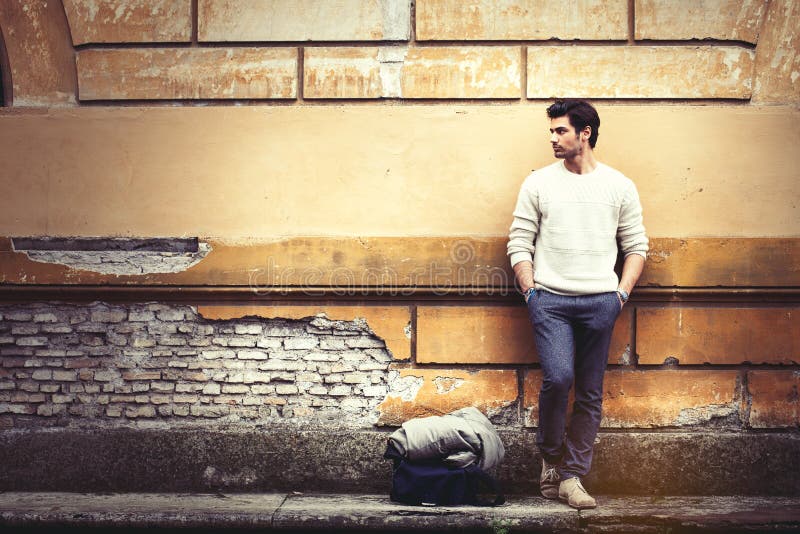 Uliczny moda modela turystyczny mężczyzna plenerowy Czekać na grunge ścianie obraz stock Uliczny moda modela turystyczny mężczyzna plenerowy Czekać na grunge ścianie obraz stock