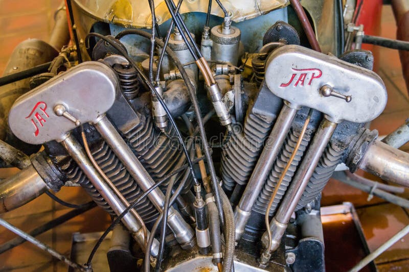 Ultra closeup of vintage V-twin engine made by J.A.P of England, showing the inclined cylinders, exhaust pipes and many cables with visible remnants of grime and engine oil. Ultra closeup of vintage V-twin engine made by J.A.P of England, showing the inclined cylinders, exhaust pipes and many cables with visible remnants of grime and engine oil