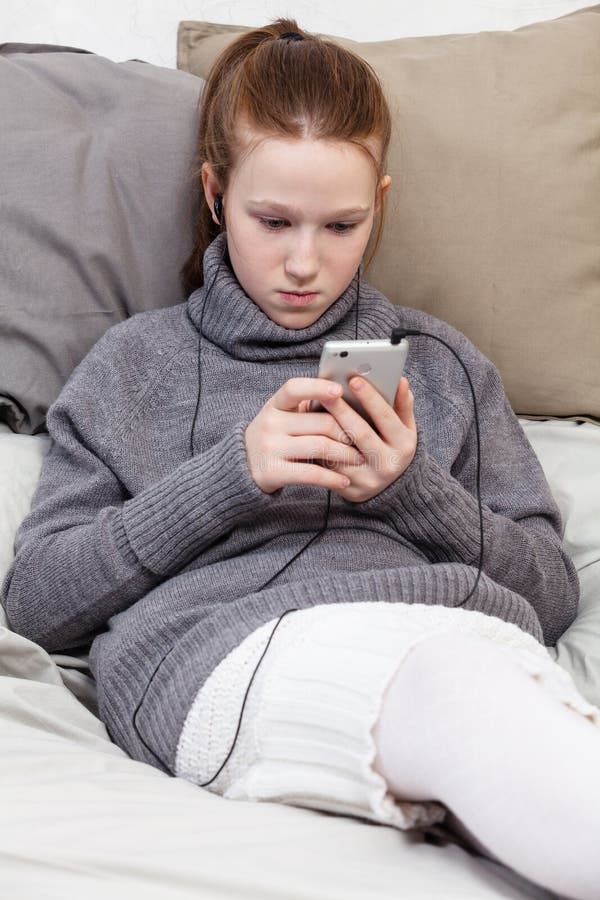Um adolescente doce nos fones de ouvido que escuta a música imagem de stock Um adolescente doce nos fones de ouvido que escuta a música imagem de stock