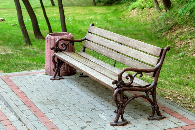 Um banco com um assento de madeira e para passar os pés forjados imagem de stock