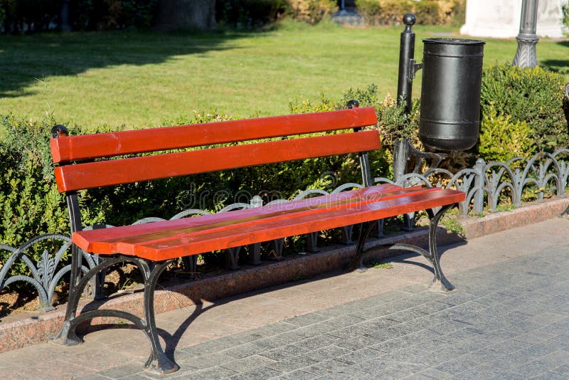 Um banco com um escaninho de lixo em um parque da cidade foto de stock royalty free