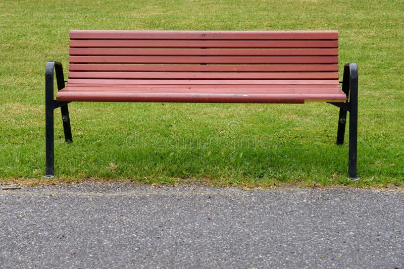 Um banco de madeira num parque com grama verde. fotos de stock