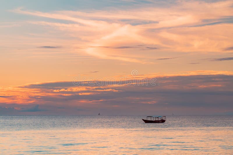 One Fishing boat in water of Indian ocean on a scenic sunset. Zanzibar, Tanzania. One Fishing boat in water of Indian ocean on a scenic sunset. Zanzibar, Tanzania.