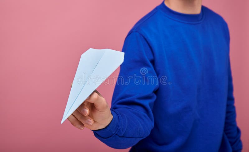 Um Cara Com Um Suéter Azul Escuro Está Parado Sobre Um Fundo Cor-de-rosa Com Um Avião De Papel Azul Imagem de Stock - Imagem de cara, está: 165246629