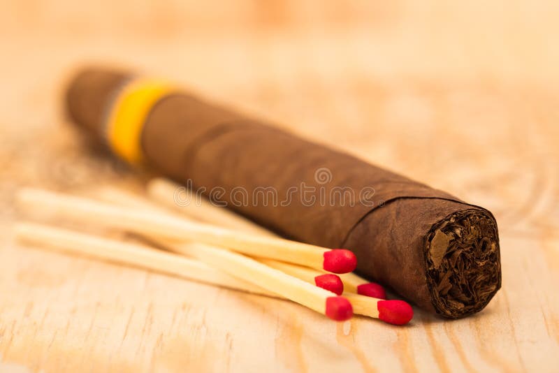 Um charuto e cinco fósforos com cabeças vermelhas. imagens de stock royalty free Um charuto e cinco fósforos com cabeças vermelhas. imagens de stock royalty free