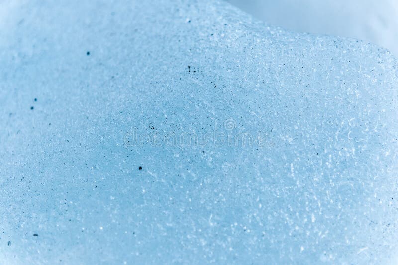 Um close-up da superfície de um fragmento de uma geleira com uma estrutura das tiras e das bolhas intercaladas com areia e fotografia de stock royalty free Um close-up da superfície de um fragmento de uma geleira com uma estrutura das tiras e das bolhas intercaladas com areia e fotografia de stock royalty free