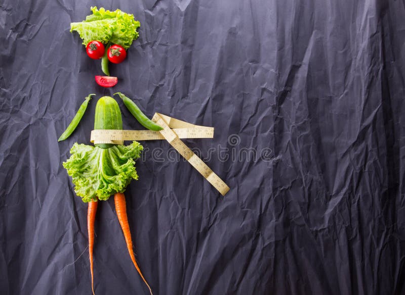 Um conceito do alimento da menina com os vegetais no fundo de papel preto Perda de peso e estilo de vida saudável Com espaço para fotografia de stock Um conceito do alimento da menina com os vegetais no fundo de papel preto Perda de peso e estilo de vida saudável Com espaço para fotografia de stock