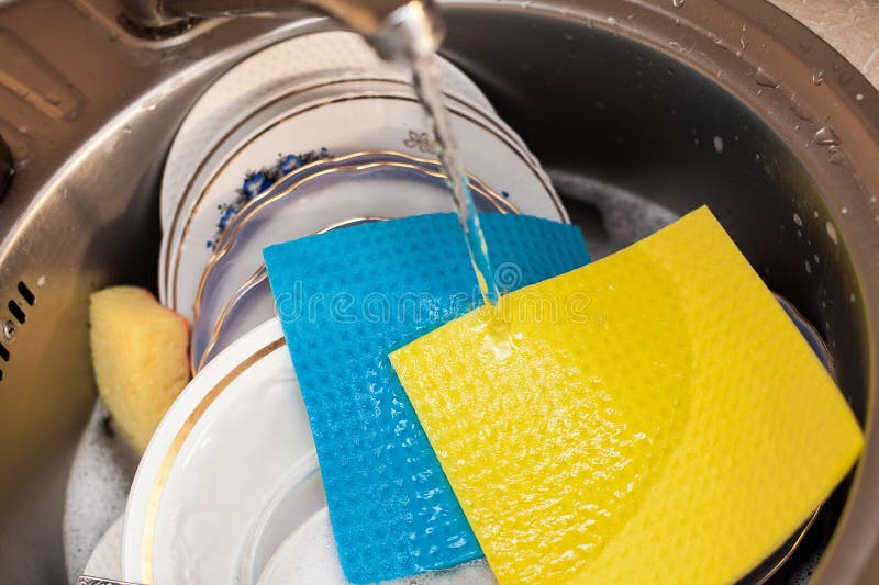Um conjunto de grandes placas de panos coloridos e uma esponja estão na bacia com água espumosa