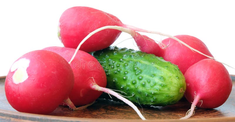 A set of basic ingredients for preparing a vitamin salad. The set of vegetables includes radish and cucumber. Usually, young onions, parsley and dill are added to the vegetable salad, everything is finely chopped and greased with vegetable oil, ground black pepper, salt, and spices are added to taste. Vegetables are placed on a clay plate. Red and green colors predominate. A set of basic ingredients for preparing a vitamin salad. The set of vegetables includes radish and cucumber. Usually, young onions, parsley and dill are added to the vegetable salad, everything is finely chopped and greased with vegetable oil, ground black pepper, salt, and spices are added to taste. Vegetables are placed on a clay plate. Red and green colors predominate.