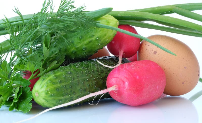 A set of ingredients for preparing a vitamin salad on a light background. The set of vegetables includes radish, chicken eggs and cucumber. Usually, young onions, parsley and dill are added to the vegetable salad, everything is finely chopped and greased with vegetable oil, ground black pepper, salt, and spices are added to taste. Red and green colors predominate. A set of ingredients for preparing a vitamin salad on a light background. The set of vegetables includes radish, chicken eggs and cucumber. Usually, young onions, parsley and dill are added to the vegetable salad, everything is finely chopped and greased with vegetable oil, ground black pepper, salt, and spices are added to taste. Red and green colors predominate.