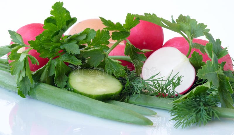 A set of ingredients for preparing a vitamin salad on a light background. The set of vegetables includes radish, chicken eggs and cucumber. Usually, young onions, parsley and dill are added to the vegetable salad, everything is finely chopped and greased with vegetable oil, ground black pepper, salt, and spices are added to taste. Red and green colors predominate. A set of ingredients for preparing a vitamin salad on a light background. The set of vegetables includes radish, chicken eggs and cucumber. Usually, young onions, parsley and dill are added to the vegetable salad, everything is finely chopped and greased with vegetable oil, ground black pepper, salt, and spices are added to taste. Red and green colors predominate.
