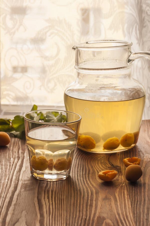 Um copo de vidro e um jarro com compota de fruto do abricó e os abricós maduros em uma tabela de madeira Sobremesa doce e saud?ve fotografia de stock royalty free Um copo de vidro e um jarro com compota de fruto do abricó e os abricós maduros em uma tabela de madeira Sobremesa doce e saud?ve fotografia de stock royalty free