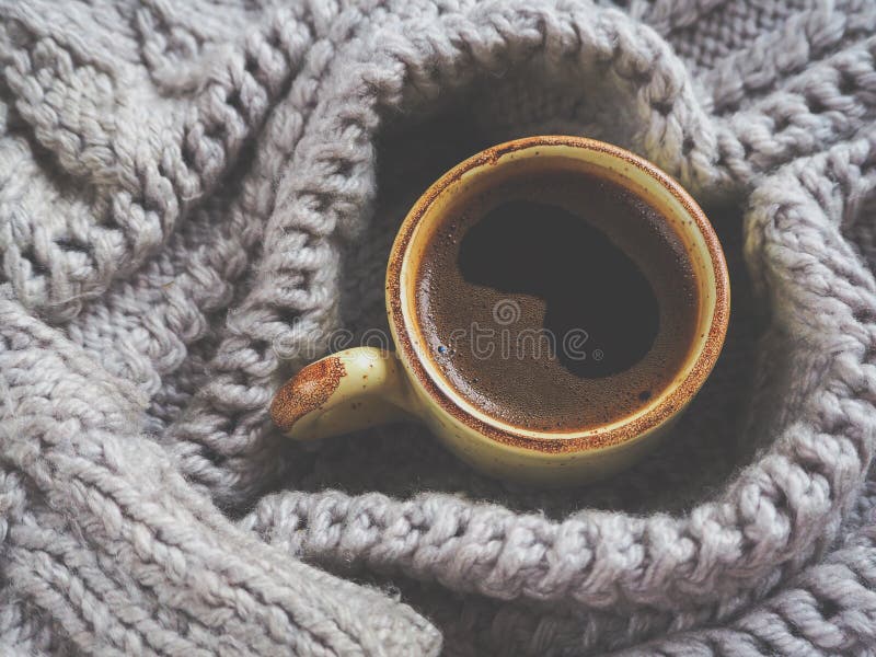 Um copo do café em uma camiseta do inverno O conceito do conforto, do aconchego e do calor home