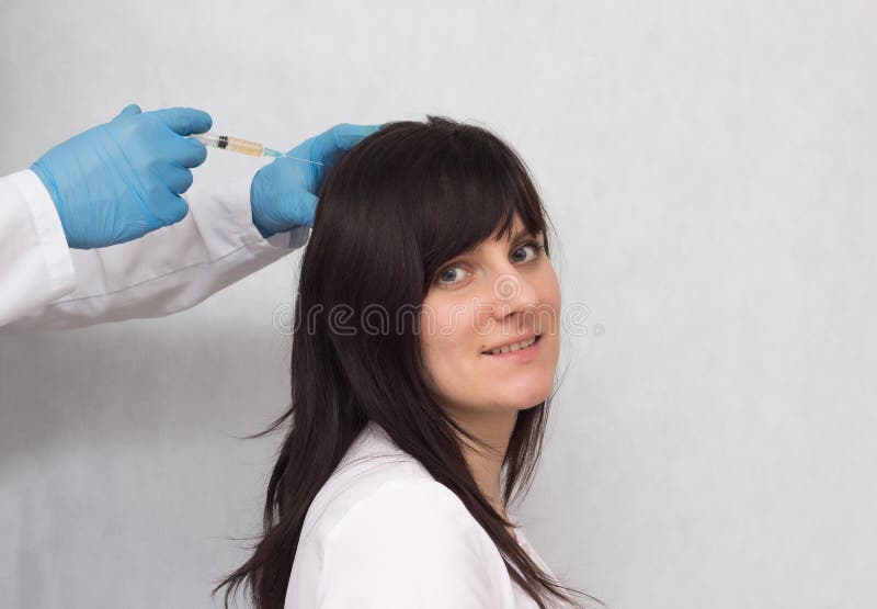 Um doutor injeta uma menina moreno delevantamento ao crescimento do cabelo e a qualidade, terapia do plasma, médica, trava imagens de stock royalty free Um doutor injeta uma menina moreno delevantamento ao crescimento do cabelo e a qualidade, terapia do plasma, médica, trava imagens de stock royalty free