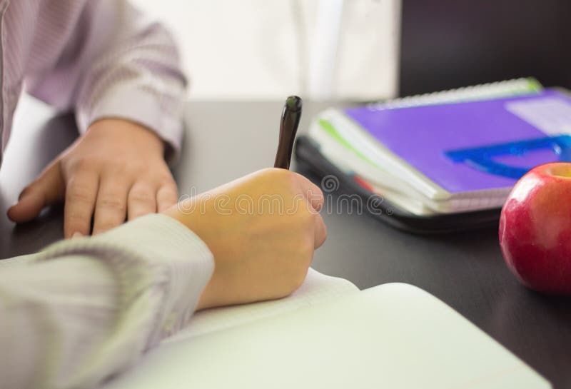 Um estudante da High School ou um estudante escrevem em um caderno em uma mesa, fazendo trabalhos de casa imagens de stock royalty free Um estudante da High School ou um estudante escrevem em um caderno em uma mesa, fazendo trabalhos de casa imagens de stock royalty free