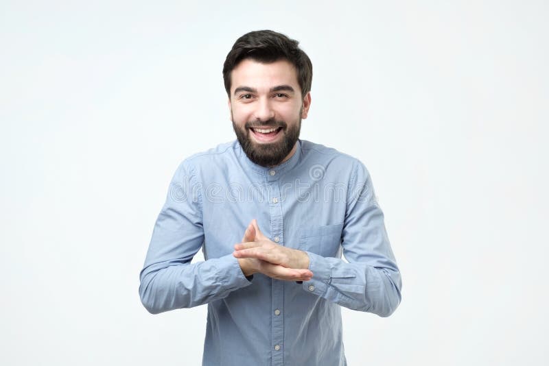 Um estudante masculino espanhol com uma barba com uma expressão esperto que fricciona suas mãos na frente dele fotografia de stock Um estudante masculino espanhol com uma barba com uma expressão esperto que fricciona suas mãos na frente dele fotografia de stock