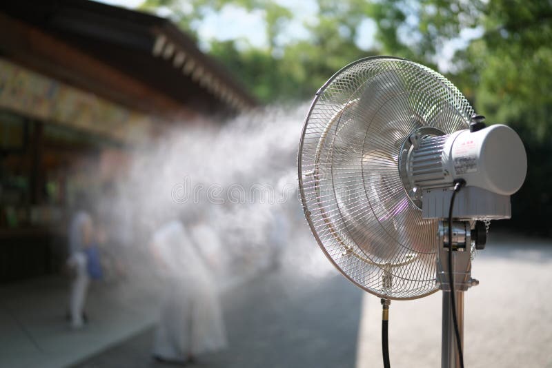 Um fã de neblina operando para resfriar pessoas visitando uma loja de lembranças em um dia quente de verão