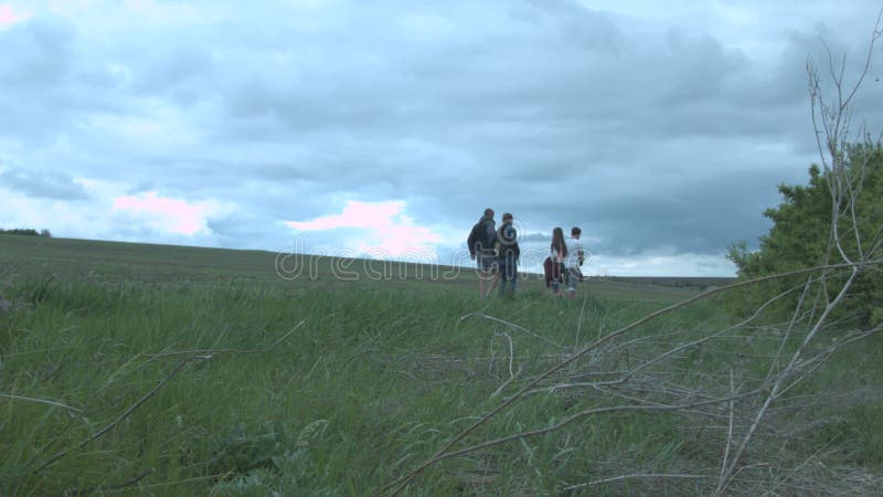 Um grupo de amigos no meio do campo contra um fundo de nuvens grossas Os amigos estão andando na natureza ao redor