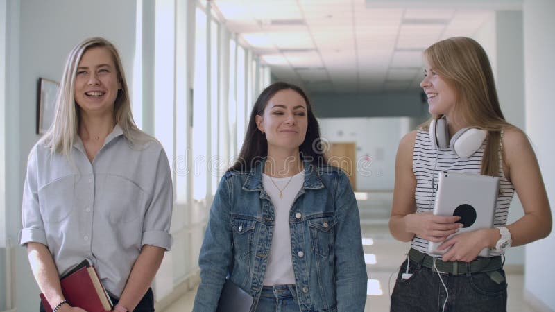 Um grupo de estudantes caminha pelo corredor da universidade, escola, faculdade, comunicação, conversa e sorriso Grande