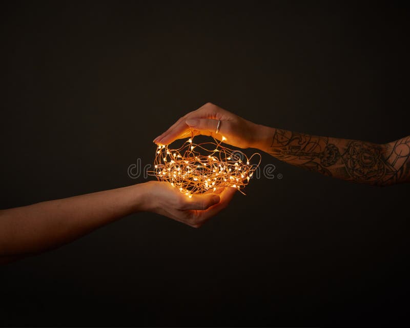 Um grupo de festões do Natal guarda uma mão masculina e fêmea com uma tatuagem em um fundo preto com espaço da cópia fotografia de stock royalty free Um grupo de festões do Natal guarda uma mão masculina e fêmea com uma tatuagem em um fundo preto com espaço da cópia fotografia de stock royalty free