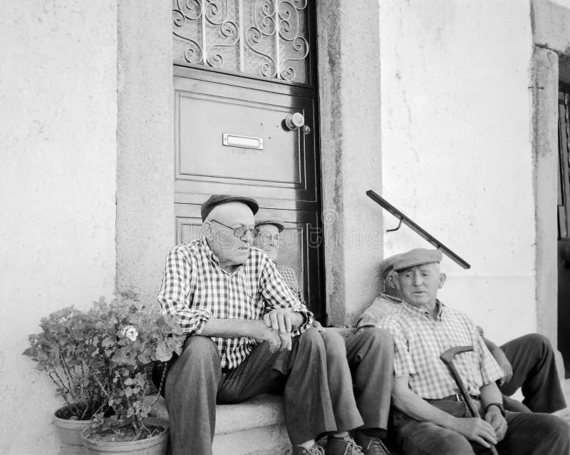 Um grupo de homens idosos que sentam-se junto fora da porta da casa, Portugal fotografia de stock Um grupo de homens idosos que sentam-se junto fora da porta da casa, Portugal fotografia de stock