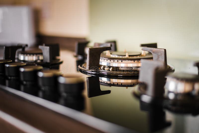 Um hob e uns botões limpos e brilhantes do fogão Tomado para dentro com a luz dourada que brilha no dispositivo foto de stock Um hob e uns botões limpos e brilhantes do fogão Tomado para dentro com a luz dourada que brilha no dispositivo foto de stock