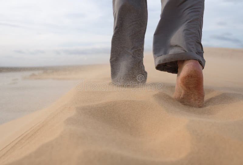 A man walks along the sandy beach. In the air, grains of sand fly from a strong wind. Photo close-up. A man walks along the sandy beach. In the air, grains of sand fly from a strong wind. Photo close-up