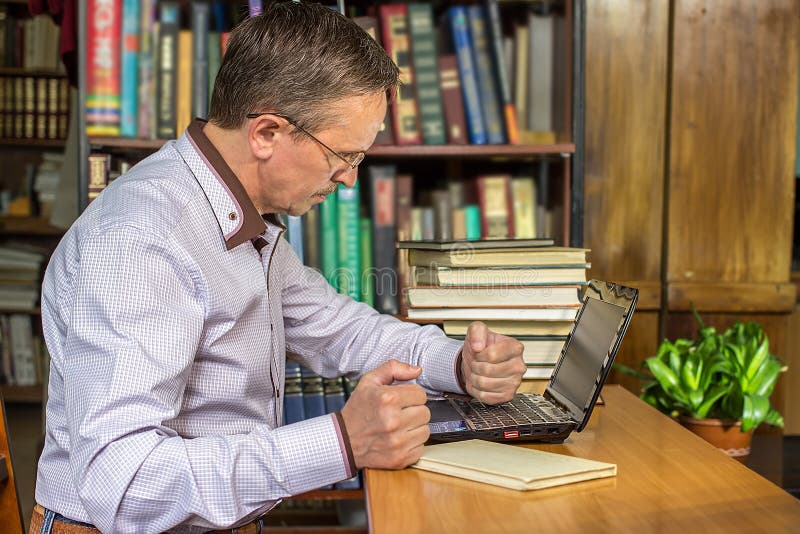 Um homem de negócios irritado perfura seu computador após a obtenção virado foto de stock royalty free Um homem de negócios irritado perfura seu computador após a obtenção virado foto de stock royalty free